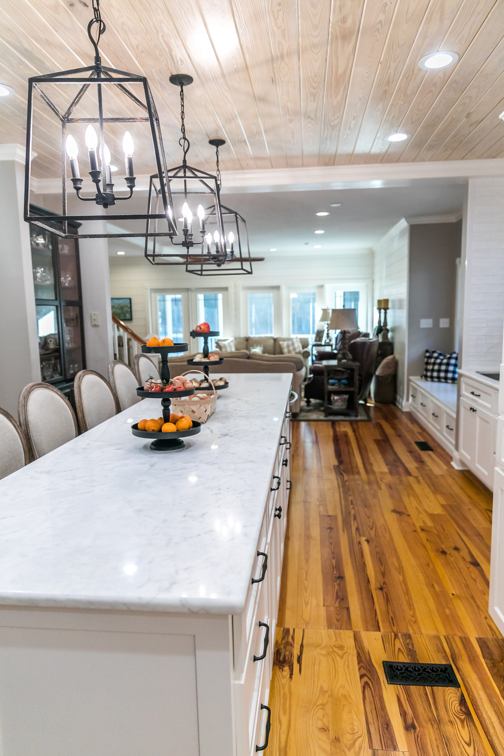 Large renovated white kitchen with textured subway tile, black iron lights and pine hardwood flooring